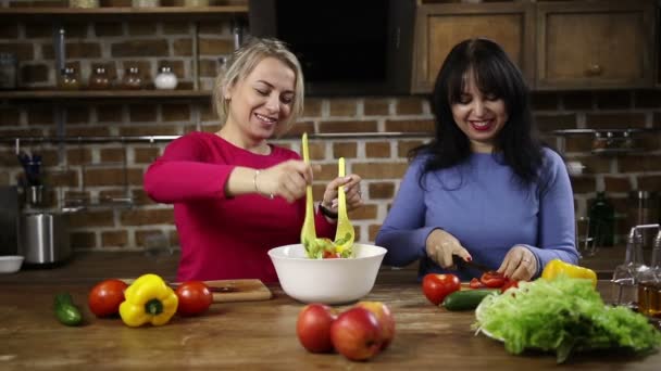 Радостная женщина средних лет, мешающая миску салата — стоковое видео