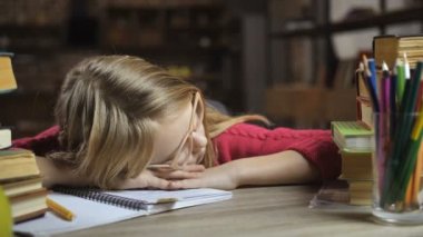 Evde masa başında uyuyan yorgun sarı saçlı kız