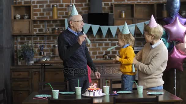 Щаслива сім'я дме роги на вечірці на день народження хлопчиків — стокове відео