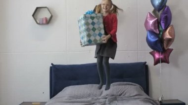 Mutlu kız yatakta büyük hediye kutusu ile atlama