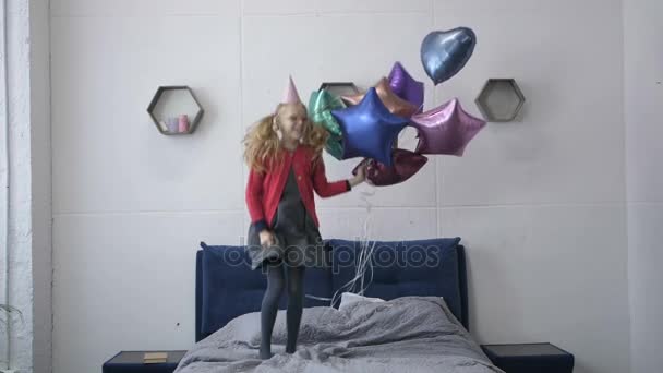 Повільний рух дівчини, що стрибає в ліжку з повітряними кульками — стокове відео
