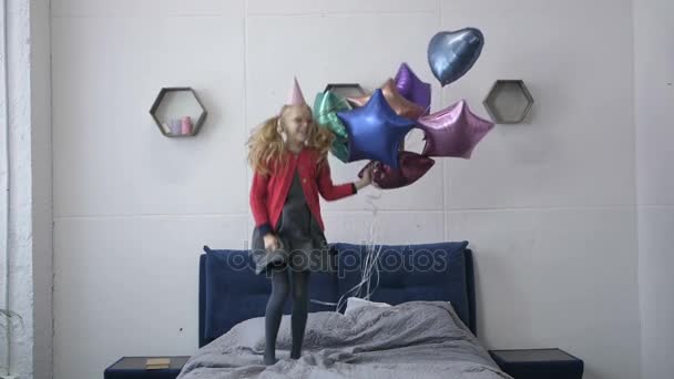 Slow motion van meisje springen op het bed met baloons — Stockvideo