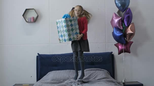 Γενέθλια κορίτσι άλματα στο κρεβάτι κρατώντας κιβώτιο δώρων — Αρχείο Βίντεο