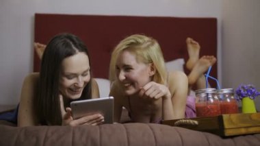 Gülümseyen genç kız yatakta yatan tablet PC'yi kullanma