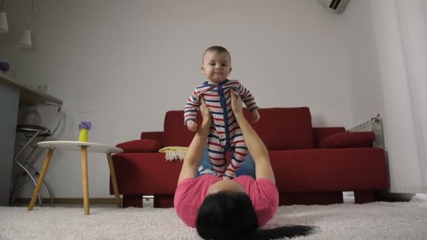 Mãe levantando o filho recém-nascido no ar em casa — Vídeo de Stock