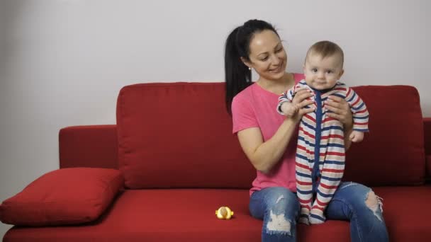 Baby boy learning to jump on sofa with mother — Stock Video