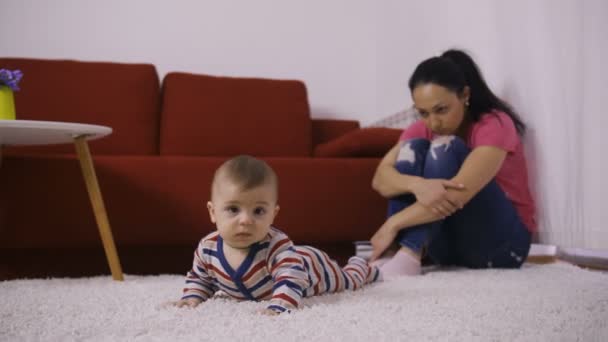 Triste mère avec les bras autour des genoux regardant bébé — Video