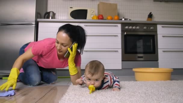 Mamá trabajadora haciendo tareas domésticas mientras cuida al bebé — Vídeo de stock