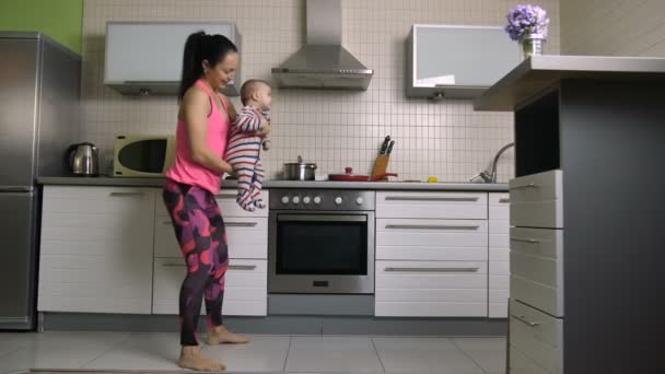 Mujer sonriente haciendo saltos con el bebé hijo en las manos — Vídeos de Stock