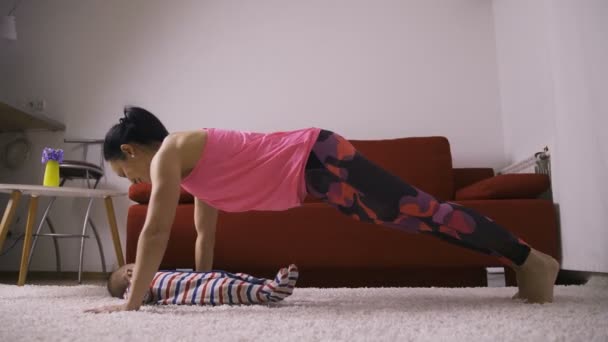 Fitness mother kissing baby doing push-ups — Stock Video