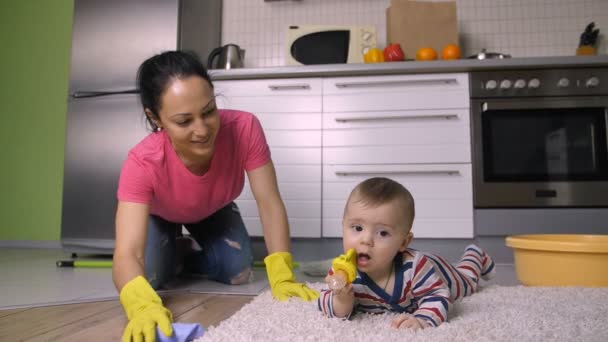 Belle mère sur les genoux plancher de lavage près de bébé — Video