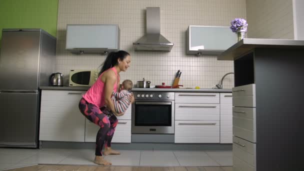 Alegre en forma mamá haciendo sentadillas con el bebé en casa — Vídeos de Stock