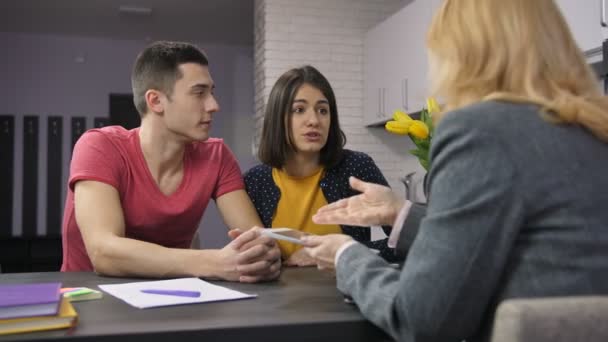 Молода пара розмовляє з агентом про іпотеку — стокове відео