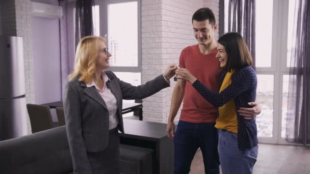 Agente imobiliário sênior dando chaves de casa para casal — Vídeo de Stock