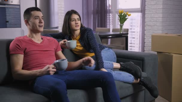 Couple regardant la télévision après avoir déménagé dans un nouvel appartement — Video