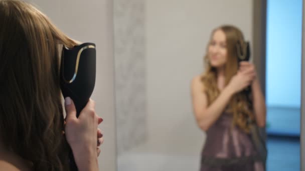 Mujer bonita rizando el pelo delante del espejo — Vídeo de stock