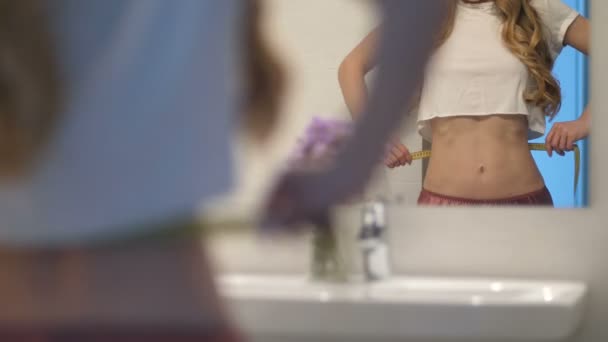 La fille mesure la taille avec du ruban adhésif et des gestes de succès — Video