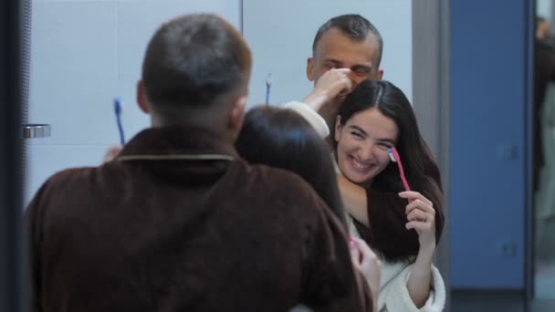 Casal feliz com escovas de dentes na frente do espelho — Vídeo de Stock