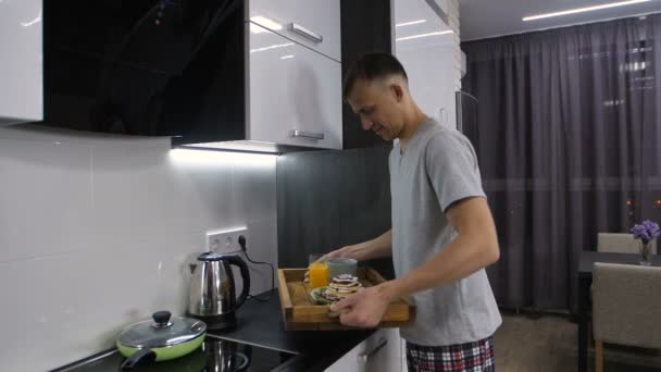 Glimlachende man in pyjama wandelen met ontbijt lade — Stockvideo