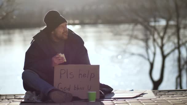 Hombre sin hogar comiendo sándwich y pidiendo ayuda — Vídeos de Stock