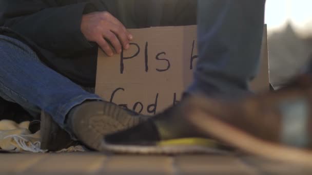 Close-up bedelaar mannetjes benen en karton ondertekenen — Stockvideo