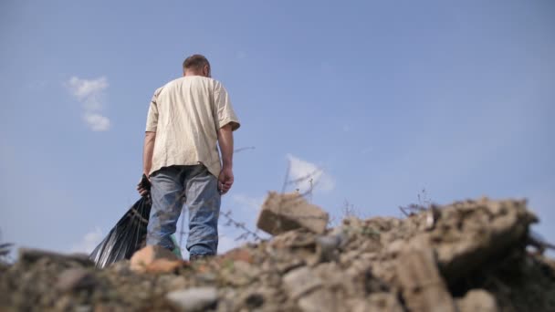 Nízký úhel muž stojící na vrcholu haldy odpadků — Stock video
