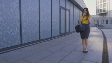 Telefon ve kahve ile yürüyen Asya iş kadın