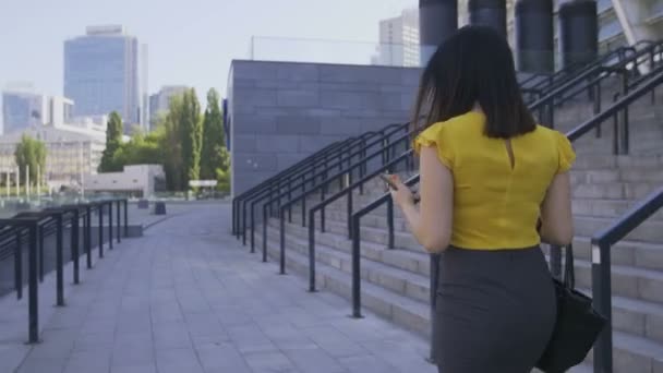 Zakenvrouw met behulp van de telefoon tijdens het wandelen naar kantoor — Stockvideo