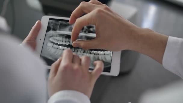 Стоматологи крупным планом смотрят на рентген на планшете — стоковое видео