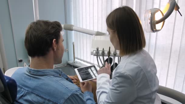 Стоматолог и пациент, изучающий рентген зубов — стоковое видео