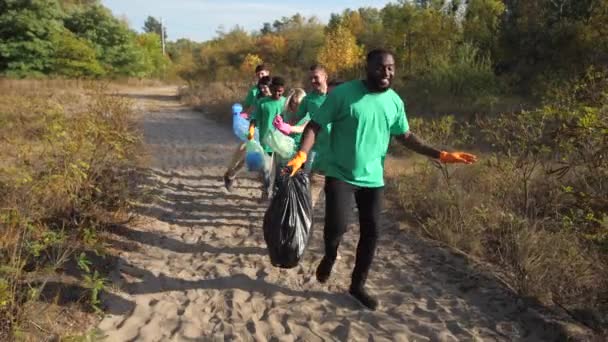 Щасливі різноманітні волонтери танцюють збираючи сміття — стокове відео