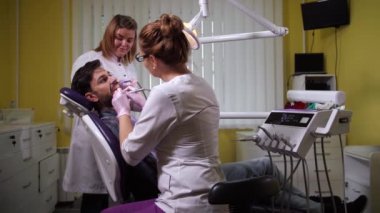 Klinikte dişlerini delen kadın dişçi.