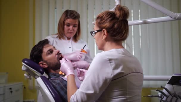 Dentista feminina selando o dente dos pacientes — Vídeo de Stock