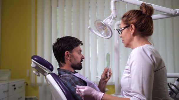 Patiënt die in de spiegel kijkt na tandheelkundige behandeling — Stockvideo