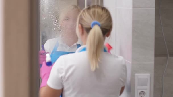 Glimlachende vrouw schoner vegen spiegel in badkamer — Stockvideo