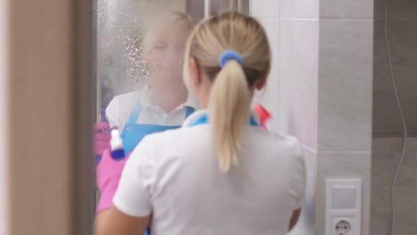 Usmívající se žena čistič otírání zrcadlo v koupelně