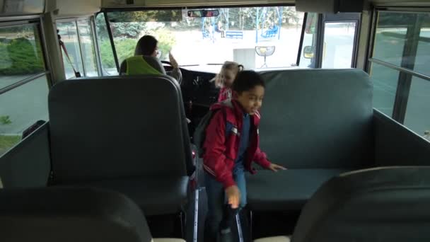 Cheerful schoolkids taking seats getting on bus — Stock Video