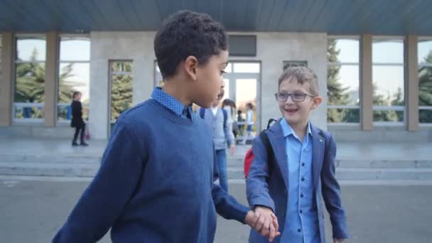 Разнообразные школьники ходят, держась за руки на улице — стоковое видео