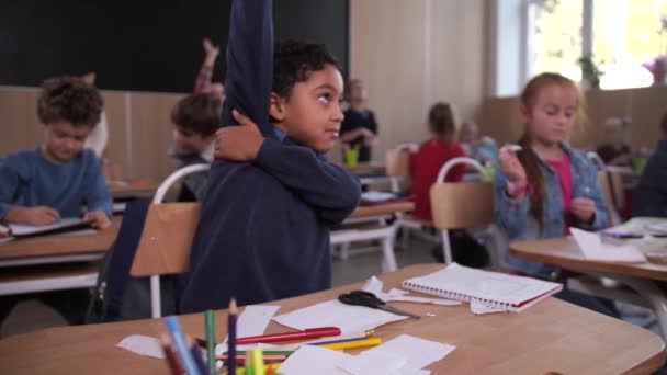 Ativo bonito menino confiantemente levantando a mão na classe — Vídeo de Stock