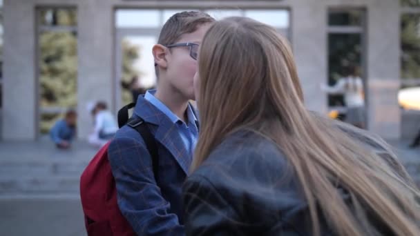 Mãe beijando pequeno filho adeus perto da escola — Vídeo de Stock