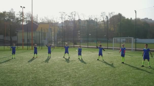 Equipo de fútbol infantil durante el calentamiento en el campo de fútbol — Vídeo de stock