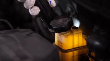 Hand of auto mechanic checking coolant level