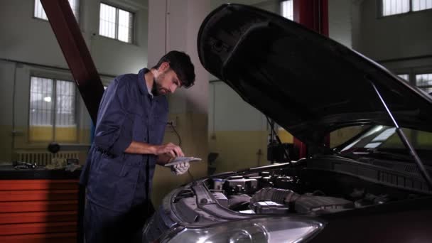 Mécanicien automobile utilisant une tablette à la recherche de pièces détachées — Video
