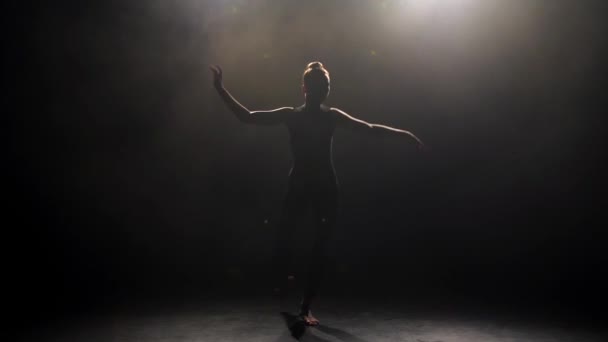 Silhouette einer jungen Tänzerin in der Dunkelheit des Studios