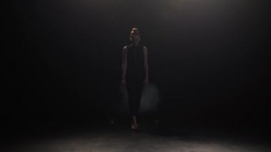 Expressive dancer appearing from dusk of stage