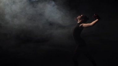 Tender girl dancing in darkness of smoky studio