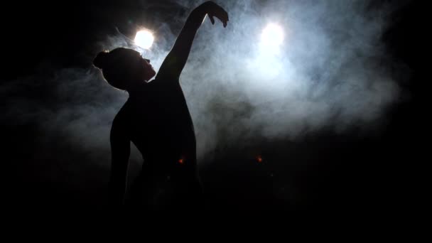 Silueta mladé tanečnice na černém podsvíceném jevišti — Stock video