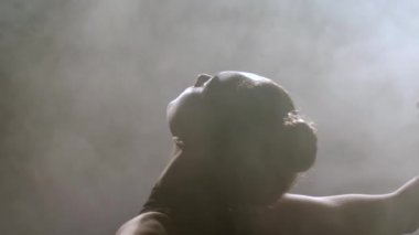 Silhouette of female dancing among puffs of smoke