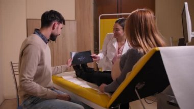 Doctor showing ultrasound picture to happy couple