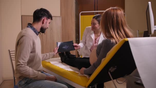 Dottore mostrando l'immagine ultrasuoni per coppia felice — Video Stock